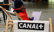 A chair with the Canal+ television logo and a person with the festival program are present...