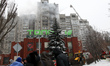A rescuer extinguishes a fire from a ladder truck at a 16-storey residential building hit...