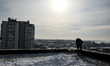 A man clears snow from the roof of a restored nine-storey building on Zaporizka Street, on...