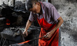In Luoping, Sichuan Province, China, on April 16, 2025, a blacksmith hand-forges scrap met...