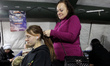 A woman braids a girl's hair at a mobile heating point in the Desnianskyi district of Kyiv...
