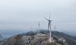 The giant wind turbines at Baiyunling Wind Farm slowly rotate with snow covering the turbi...