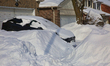 Piles of snow surround a vehicle covered with snow the morning after a winter snowstorm hi...
