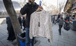An Iranian vendor holds a dress while standing on a sidewalk near the Grand Bazaar in sout...