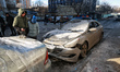 People stand by cars damaged by an overnight Russian drone strike in Odesa, Ukraine, on Fe...