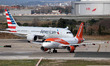 An easyJet Airbus A319-111 and an American Airlines Boeing 787-8 Dreamliner maneuver on th...