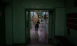A firefighter from Sumy carries a wooden board to cover the shattered windows of a childre...
