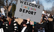 A demonstrator holds a placard reading ''welcome immigrants, deport racists'' during a ral...