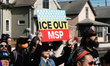 A demonstrator holds a placard reading ''ice out msp'' during a rally and demonstration at...
