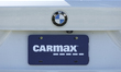 A detail view of the CarMax logo on a branded placeholder plate on a BMW vehicle in Inglew...