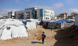 A boy walks with a water container after filling it up from a mobile cistern in Gaza City,...
