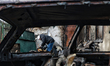 A woman looks for belongings in the ruins of a house that catches fire due to an overnight...