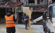 Utility workers clear debris at the scene of a Russian strike drone hit on a residential h...