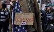 A demonstrator stands for a portrait as people march in New York City, United States, on F...