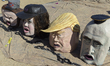 Oversized caricature heads depicting Stephen Miller, Kristi Noem, and Donald Trump are pla...