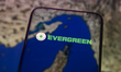 The logo of the Evergreen shipping group appears on a smartphone screen placed on a reflec...