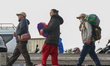 Nepali voters carry luggage and walk towards the designated vehicle as they prepare to lea...