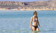 View of a young woman wearing a bikini in Balos lagoon with the warm sandy beach on the Gr...