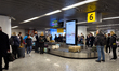 A baggage carousel at Warsaw Chopin Airport is seen with passengers waiting for their lugg...