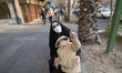 A young Iranian boy sits with his mother and points up after hearing the sound of a fighte...