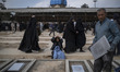 An Iranian woman mourns as she sits beside newly dug graves during funerals for those kill...