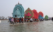Devotees carry idols of gods and goddesses through the waters of Chilika Lake during the 1...