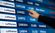 A passenger checks the Lufthansa flight status, and the airport arrivals and departures bo...