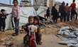 Palestinians inspect the site of an Israeli strike on a tent camp sheltering displaced peo...