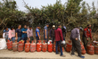 Nepali consumers wait in line carrying empty LPG cylinders as they rush to gas depots to r...