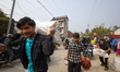 Nepali consumers carry refilled LPG cylinders as they rush to gas depots to refill them as...