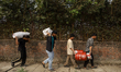 Nepali consumers carry refilled LPG cylinders as they rush to gas depots to refill them as...