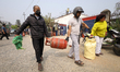 Nepali consumers carry refilled LPG cylinders as they rush to gas depots to refill them as...
