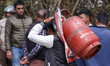 A Nepali consumer carries refilled LPG cylinders as they rush to gas depots to refill them...