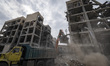 A loader works on the ruins of buildings destroyed during the U.S.-Israeli military campai...