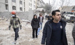 Iranian people stand in a targeted area outside buildings that are destroyed during the U....