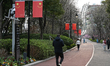 SHANGHAI, CHINA - MARCH 8: 
 A man walks on a path lined with bushes and Chinese flags in...