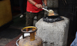 A man cooks using coal-fired ovens amid a shortage of commercial LPG cylinders in Kolkata,...