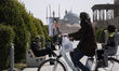 An Iranian woman rides a bicycle past a portrait of Iran's new Supreme Leader, Ayatollah M...