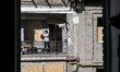 A woman stands on the balcony of an apartment building damaged by a Russian strike with gu...
