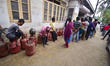 People stand in a long queue to collect LPG cylinders after information about availability...