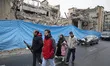 An Iranian family walks past a police facility that is destroyed in an attack during a ral...
