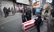 Veiled Iranian girls flash the victory sign and place their feet on a coffin symbolizing t...