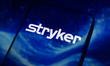The Stryker Corporation logo appears on the screen of a smartphone placed on a reflective...