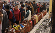 Nepali consumers wait in queue for their turn to take the half-filled gas cylinder at the...