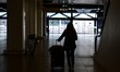 A travel agent with luggage stands in the airport terminal during the strike by security a...