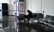 A travel agent with luggage stands in the airport terminal during the strike by security a...