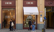 The Dior luxury fashion boutique storefront displays logo signage and attracts shoppers on...