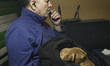An Iranian man holds his pet and puffs on a cigarette while sitting at a café at night in...