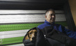 An Iranian man holds his pet and sits at a cafe whose shutter is closed to protect custome...