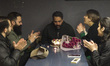 A young Iranian man makes a wish as he blows out a candle while his friends clap to congra...